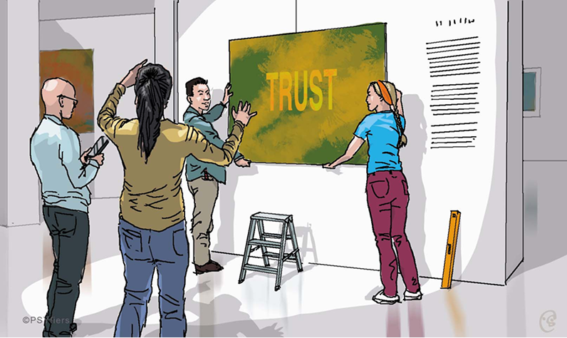 Team members hanging a canvas labeled “TRUST” during a collaborative team building moment.